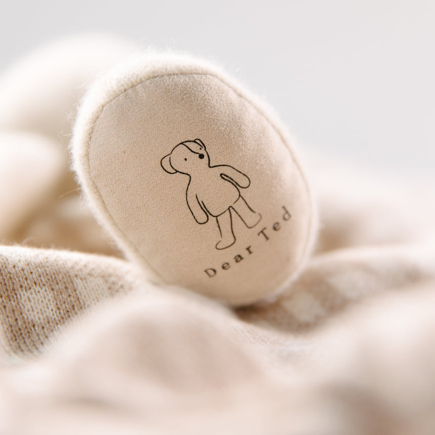 Round beige footpad with 'Dear Ted' branding on a soft beige fabric background